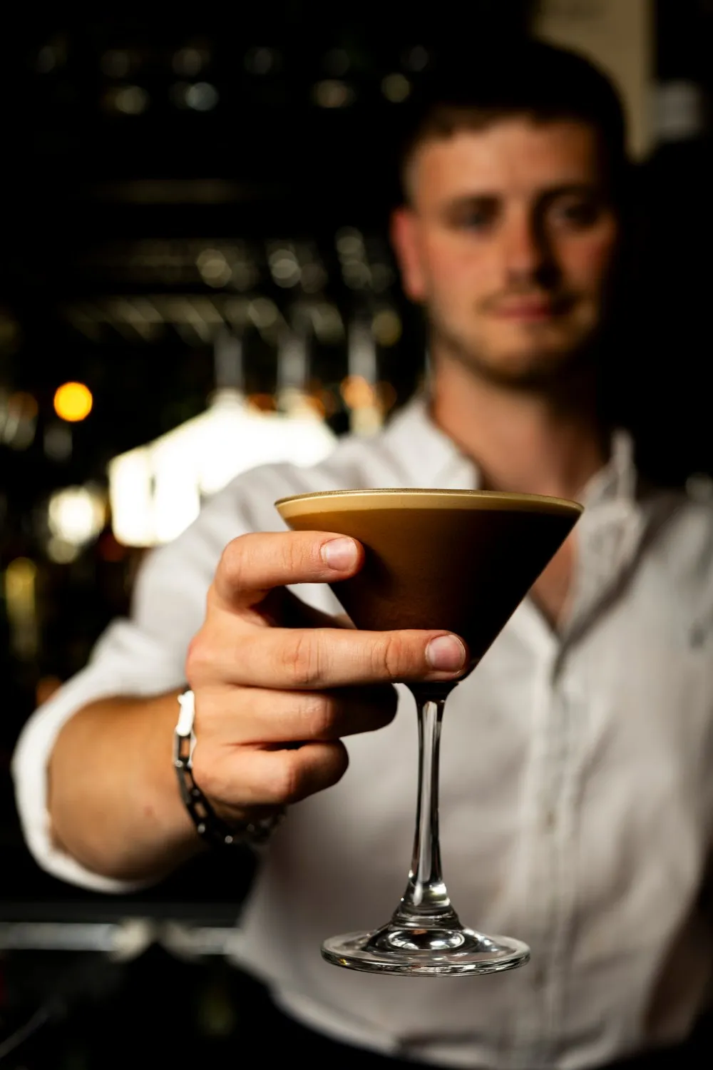 Bartender holding out an espresso martini across the bar at Bosun Restaurant.
