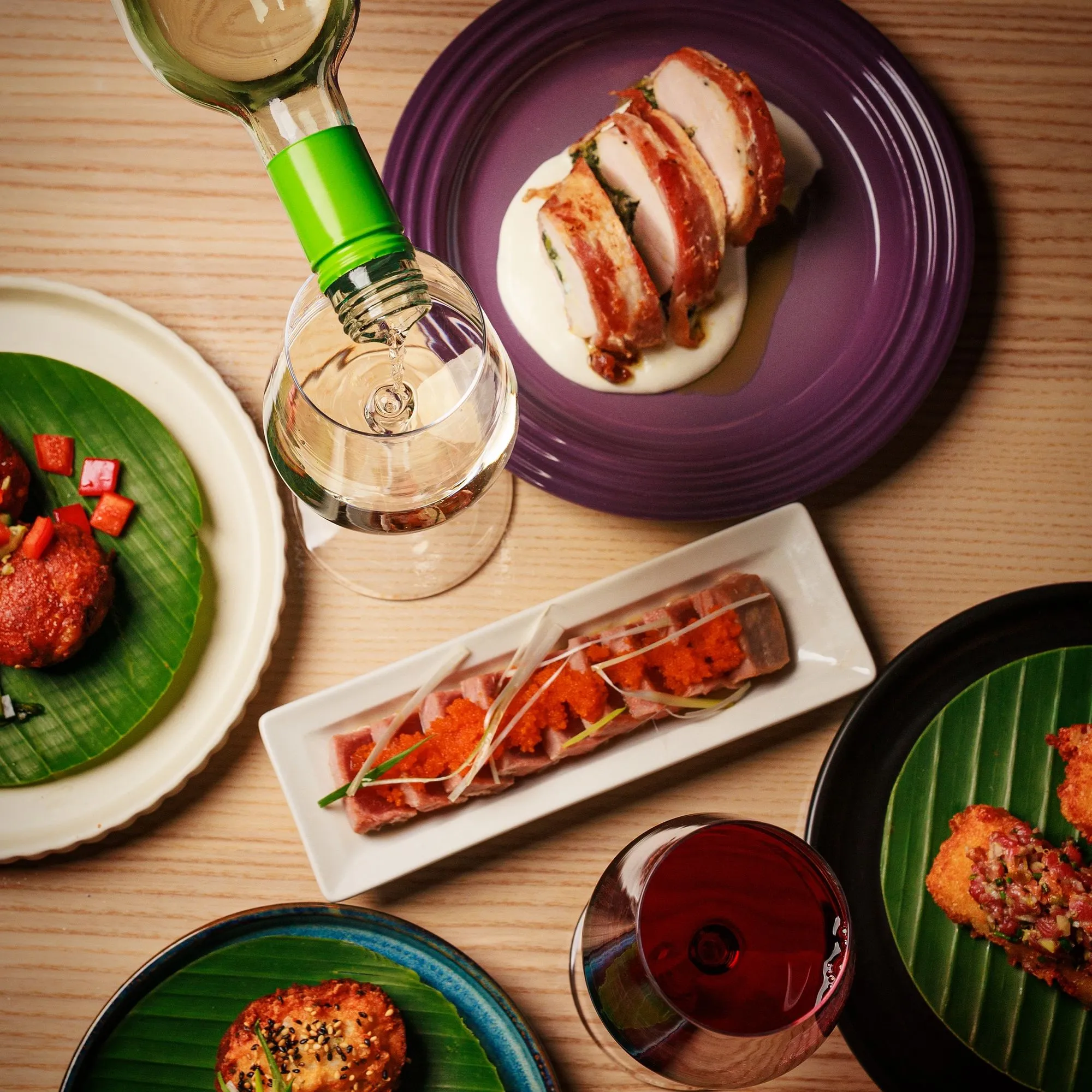 Overhead spread of plated dishes and wine at Mina's Table.