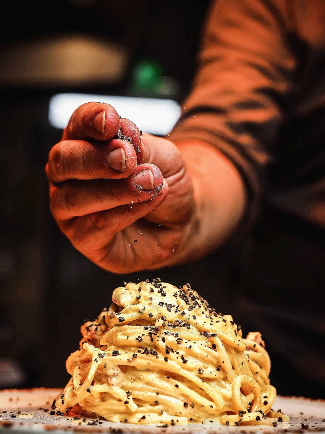 Chef finishing a nest of creamy spaghetti with cracked black pepper at Sapori.